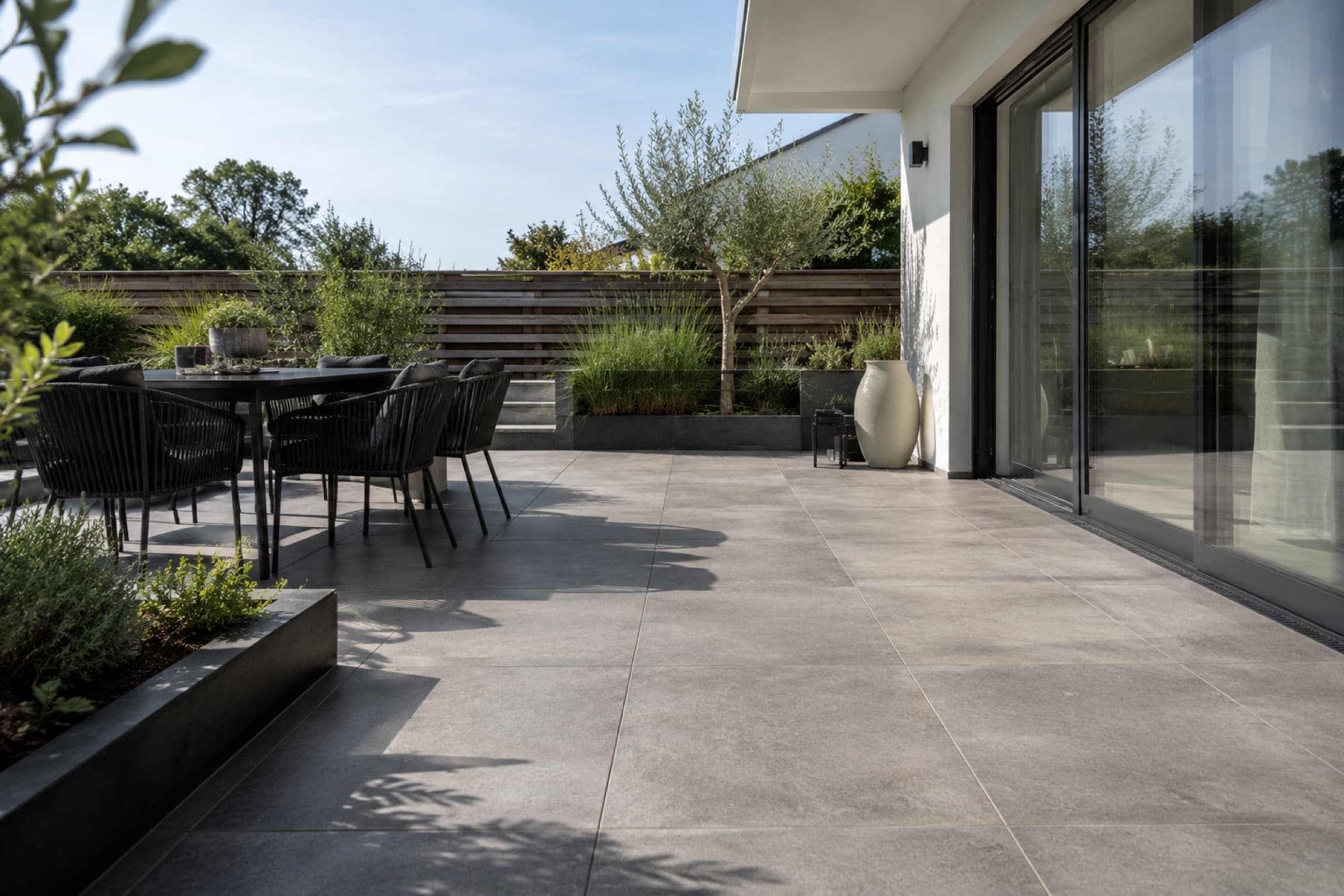 Sanierte Terrasse mit großformatigen grauen Feinsteinplatten